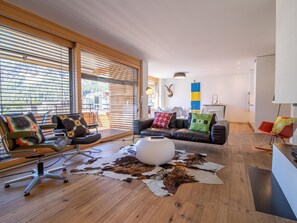 Ett modernt vardagsrum med en lädersoffa, en rund pall och en matta av kohud.