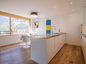 A modern kitchen with a central island, a view of mountains through a large window, and a unique wall decoration. - Salis 06 by Arosa Holiday Appartement/Fewo, Dusche und Bad, WC, 3 Schlafräume by Interhome (Arosa)