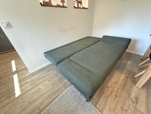 A room with a foldable bed, a patterned rug, and wall-mounted artwork. - Chalet Lucia 1 (EG) # 3-bed apartment, Dusche, WC 3-bed apartment, Dusche, WC by Interhome (Leukerbad)