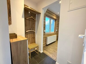 A narrow hallway with a wooden wardrobe, a radiator, and a window with a view of trees. - Chalet Lucia 1 (EG) # 3-bed apartment, Dusche, WC 3-bed apartment, Dusche, WC by Interhome (Leukerbad)