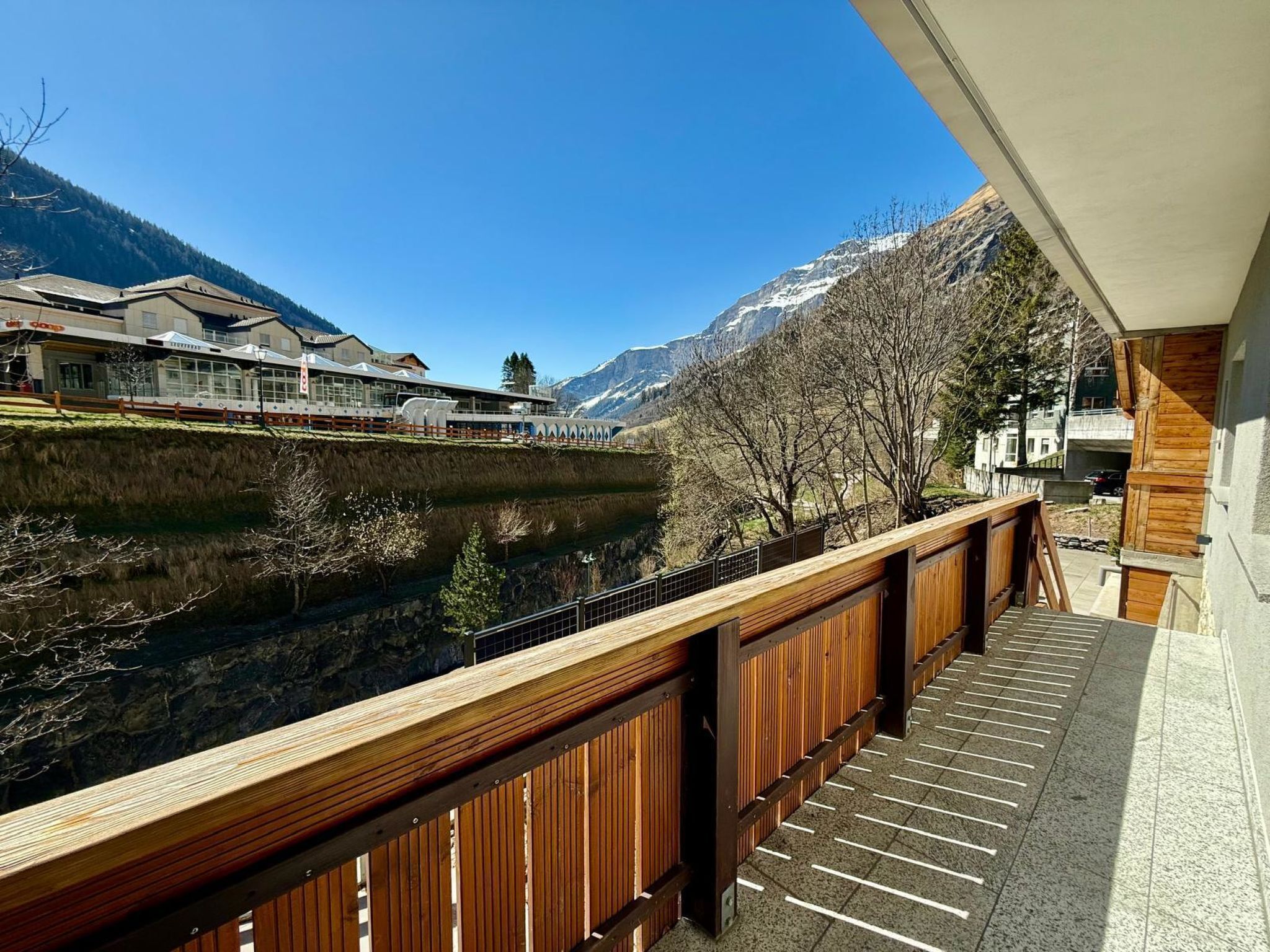 Ein Balkon mit Blick auf einen Fluss, Berge und Gebäude.