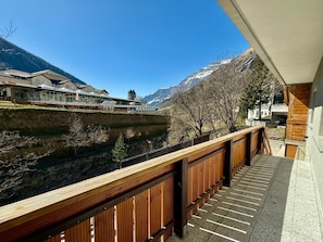 Ein Balkon mit Blick auf einen Fluss, Berge und Gebäude.