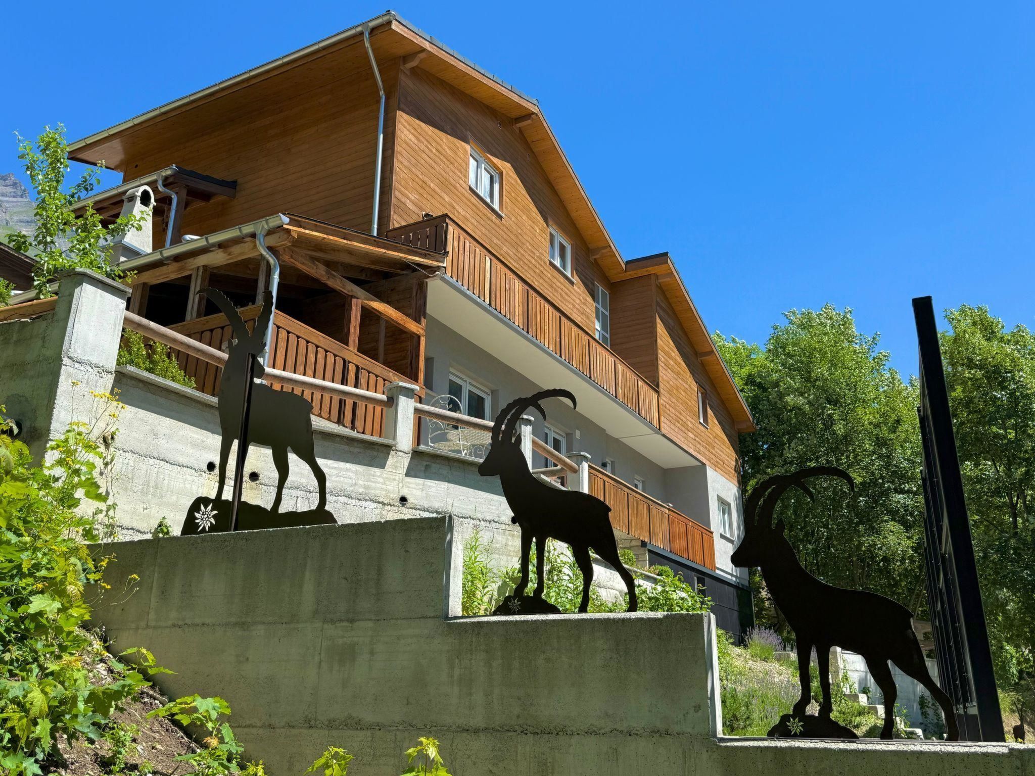 Un chalet en bois à deux étages, doté d’un balcon et entouré de verdure.