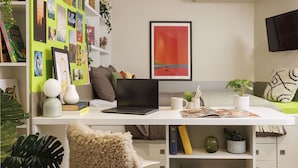Un espacio de oficina moderno con un escritorio, ordenador portátil, libros y objetos decorativos.