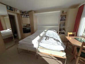 A compact room with a single bed, a small desk, and a bookshelf. - Apollo 47 # 2-bed apartment, Dusche, WC 2-Bettwohnung, Dusche, WC by Interhome (Leukerbad)