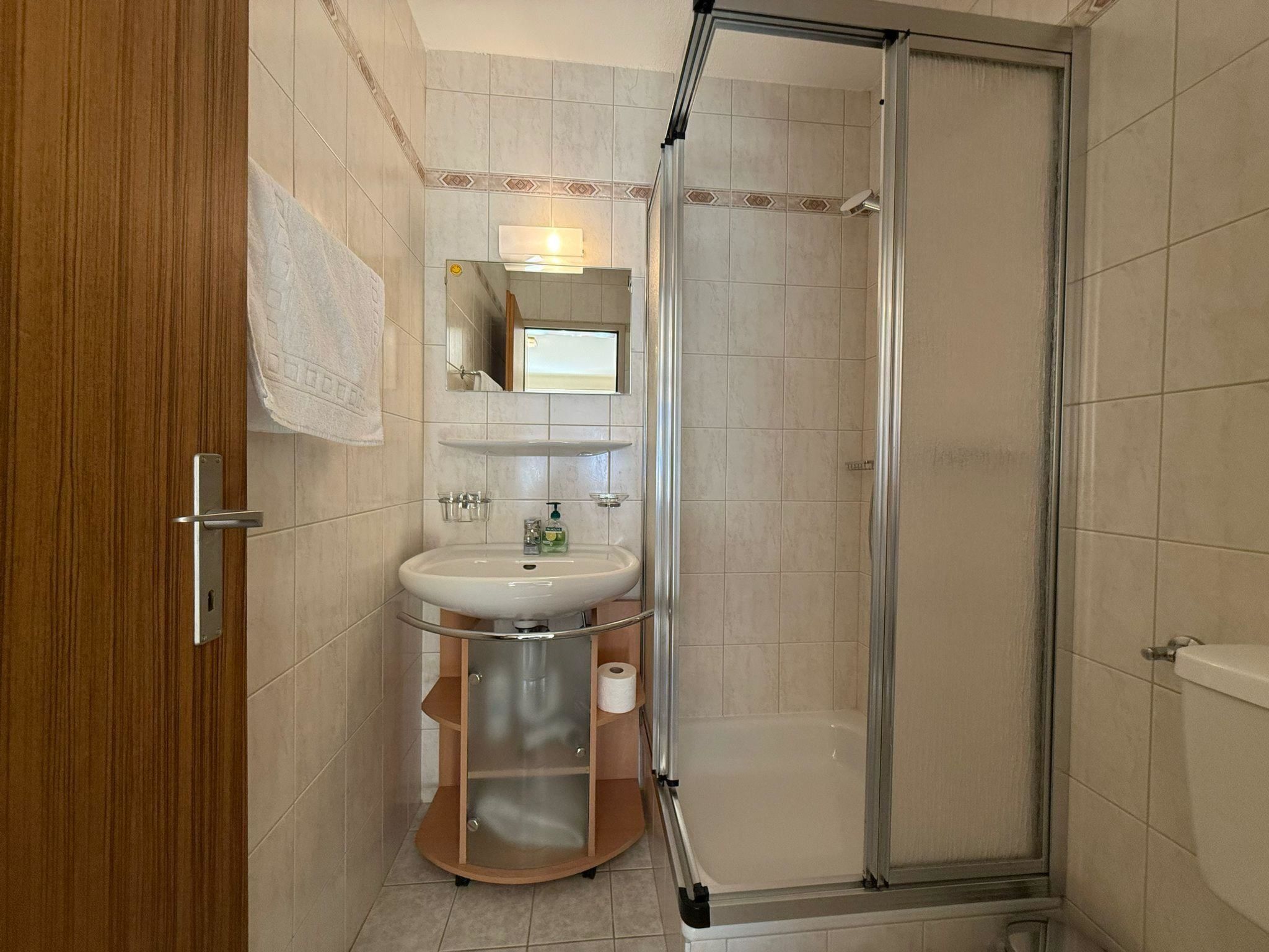 A bathroom with a shower, sink, and mirror.
