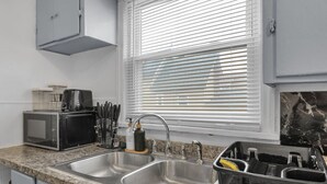 Una cocina con un lavamanos doble, un tostador, una cafetera y un bloque de cuchillos.