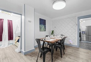 Een moderne eetruimte met een houten tafel, zwarte stoelen en een wand met een geometrisch patroon.