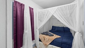 Un dormitorio con cama, cortinas blancas y dosel.