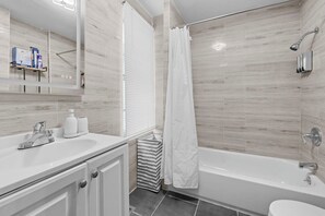 Een moderne badkamer met een badkuip, douche, wastafel en spiegel.