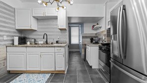 Una cocina moderna con armarios blancos, un refrigerador de acero inoxidable y una isla central con pileta.