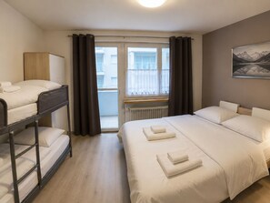 A hotel room with a bunk bed, a double bed, a radiator, a window with curtains, and a painting on the wall. - Residenz Siesta Leukerbad # 4-bed apartment, Bad, WC by Interhome (Leukerbad)