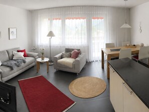 Ein modernes Wohnzimmer mit Sofa, Sesseln, Couchtisch und Esstisch.