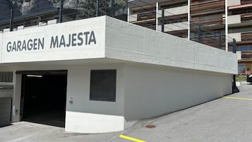 Einfahrt einer Parkgarage mit der Beschriftung 'GARAGEN MAJESTA', mit einer Betonfassade und einem Metallgeländer.