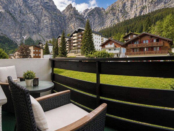 A balcony with wicker furniture, a small table, and a potted plant. - Majesta Leukerbad # 2-bed apartment, Dusche, WC by Interhome (Leukerbad)