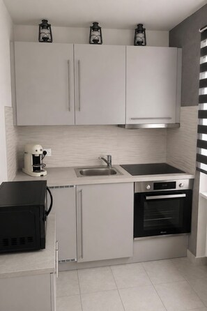 Una cocina moderna con armarios blancos, una cafetera, un fregadero, una hornalla y un horno.