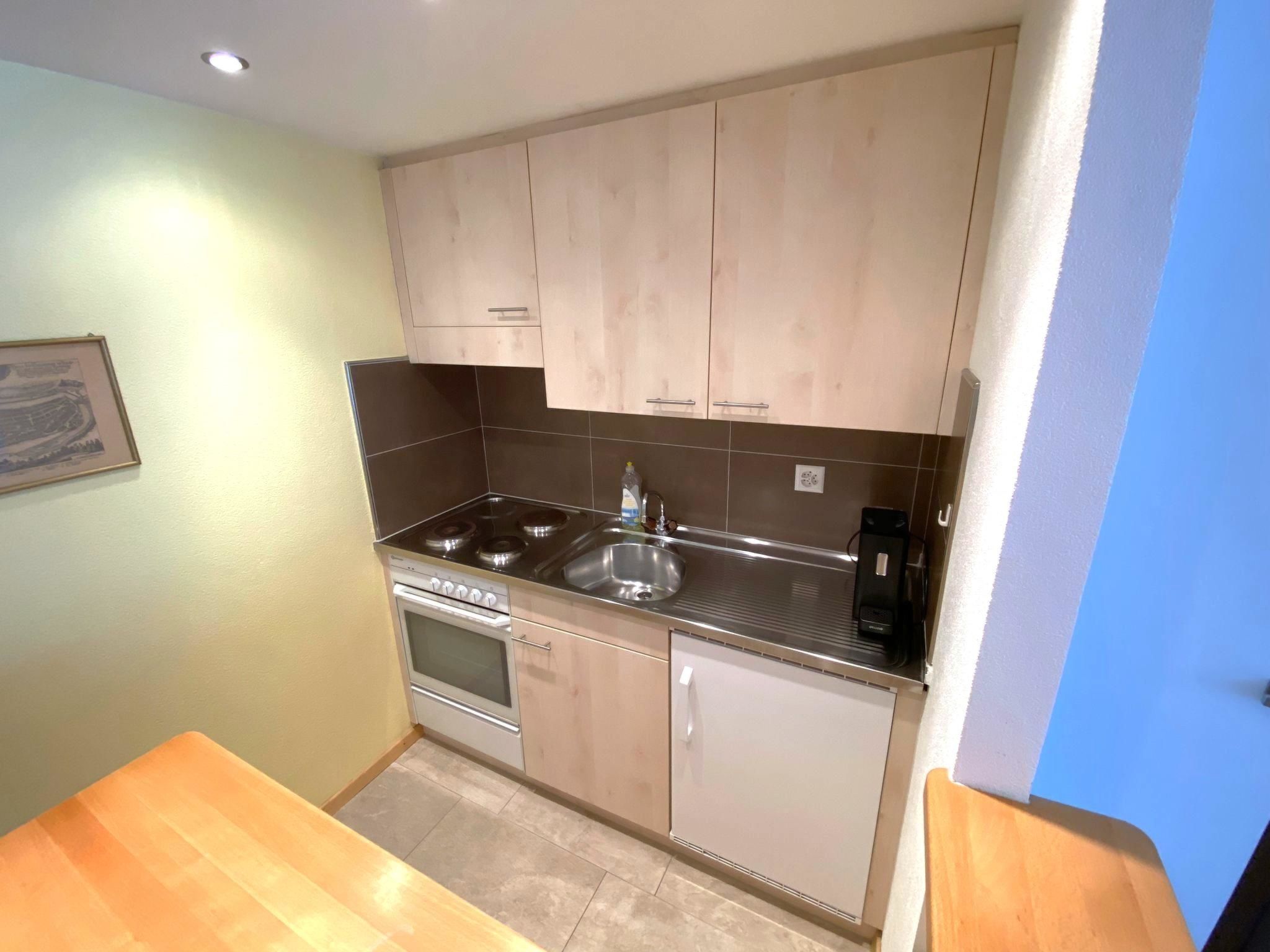 A compact kitchen with a stove, sink, and cabinets.