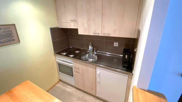 A compact kitchen with a stove, sink, and cabinets. - Adler 82 # 2-bed apartment, Dusche, WC 2-Bettwohnung, Dusche, WC by Interhome (Leukerbad)