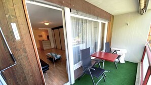 A room with a sliding glass door leading to a balcony, a small table, a chair, and a sofa. - Adler 82 # 2-bed apartment, Dusche, WC 2-Bettwohnung, Dusche, WC by Interhome (Leukerbad)