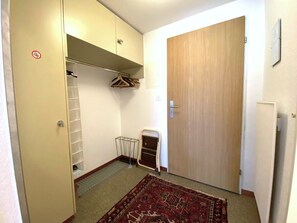 Um quarto pequeno com um guarda-roupa, um radiador, uma porta e um tapete estampado.