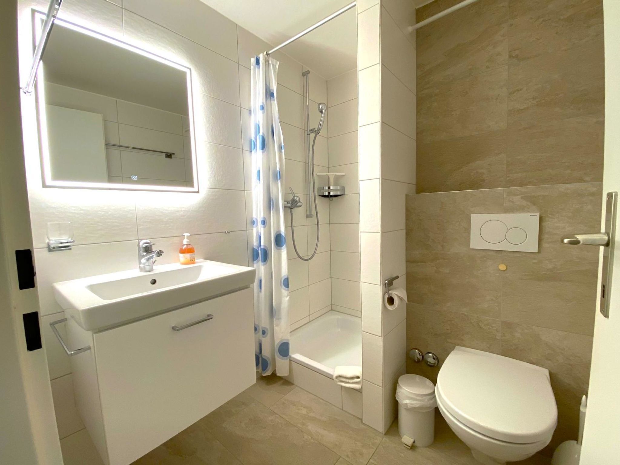 A bathroom with a sink, toilet, shower, and a mirror.
