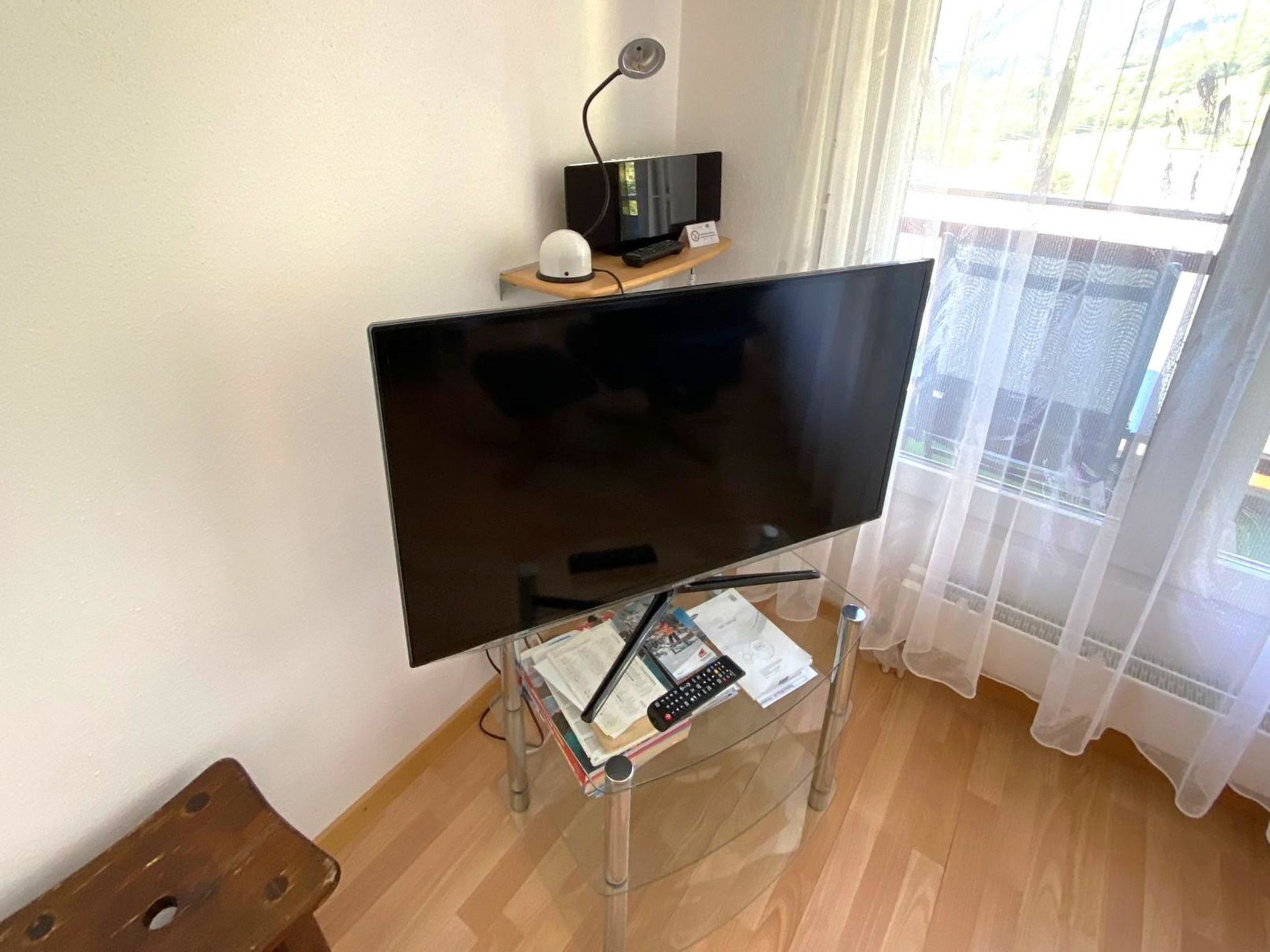 En tv-apparat placerad på ett tv-bord, med en fjärrkontroll och papper under.