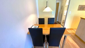 A dining area with a wooden table, four black chairs, a hanging light fixture, and a mirror on the wall. - Adler 82 # 2-bed apartment, Dusche, WC 2-Bettwohnung, Dusche, WC by Interhome (Leukerbad)
