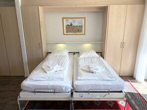 A room with two single beds, a framed painting on the wall, and a window with curtains. - Salute 109 # 4-bed apartment, Dusche, WC 4-Bettwohnung, Dusche, WC by Interhome (Leukerbad)