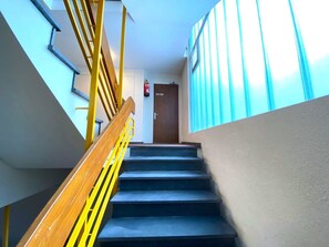 A staircase with wooden handrails and a fire extinguisher mounted on the wall. - Salute 109 # 4-bed apartment, Dusche, WC 4-Bettwohnung, Dusche, WC by Interhome (Leukerbad)
