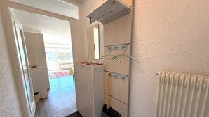Een gang met een radiator, een bezem en een spiegel aan de muur.