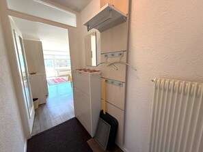 Ein Flur mit Heizkörper, Besen und Spiegel an der Wand.