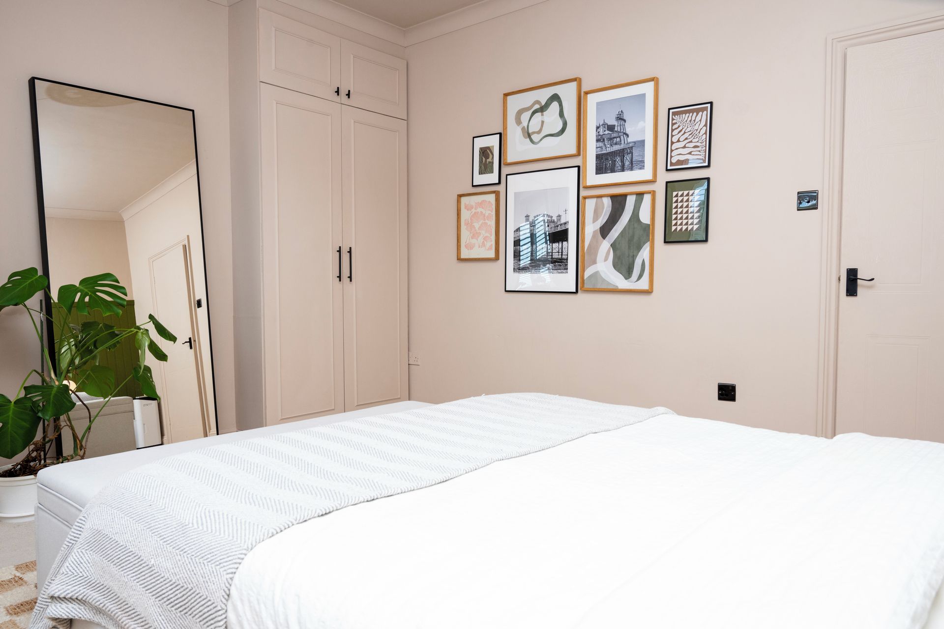 Une chambre à coucher avec un lit, un grand miroir et un mur orné de tableaux encadrés.