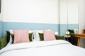 A bed with striped bedding, green pillows, and a bedside table with a lamp. - 2BDR Brighton Retreat with Courtyard Garden (Brighton and Hove)
