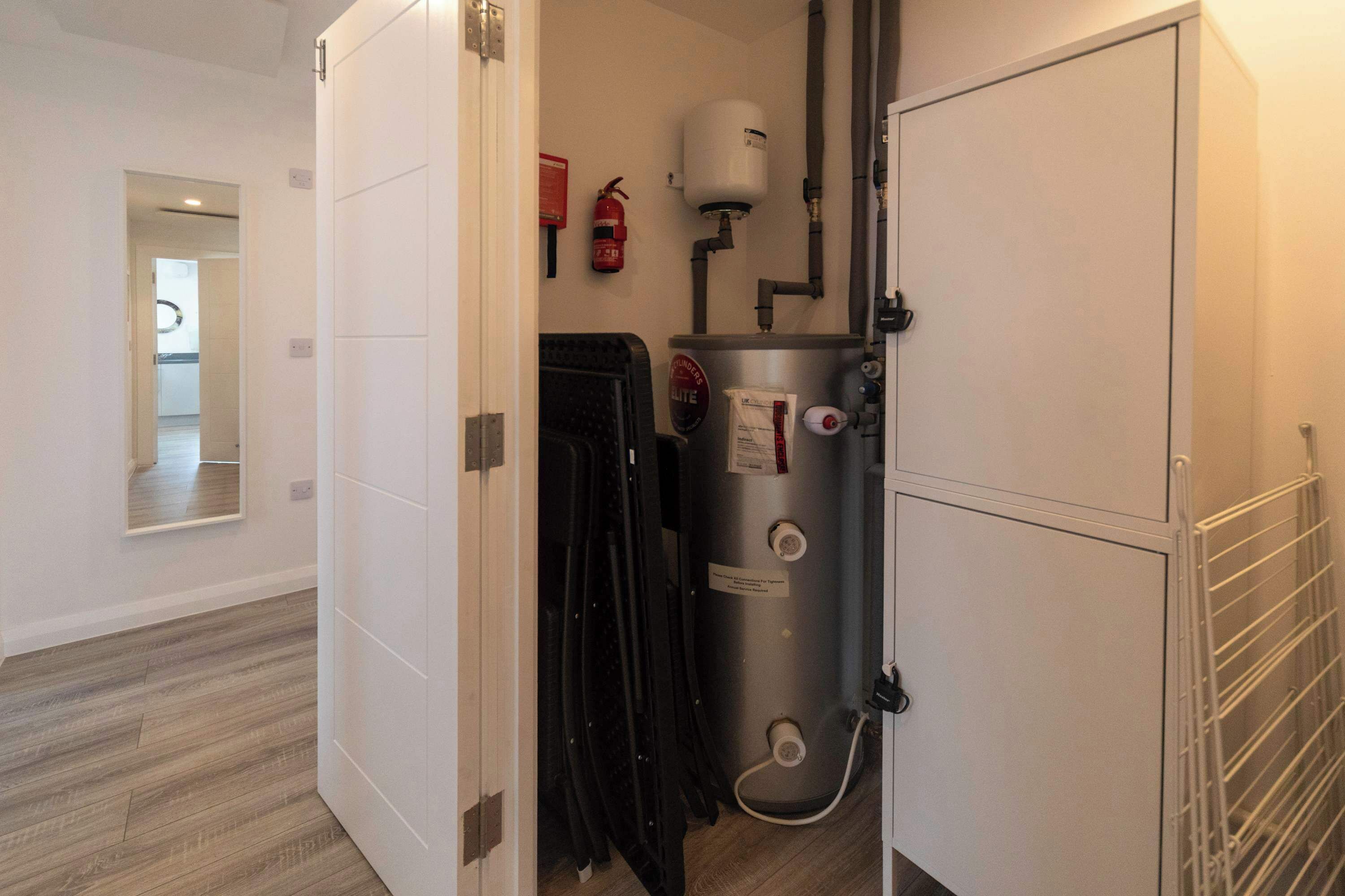 A room with a water heater, a fire extinguisher, and a metal rack.