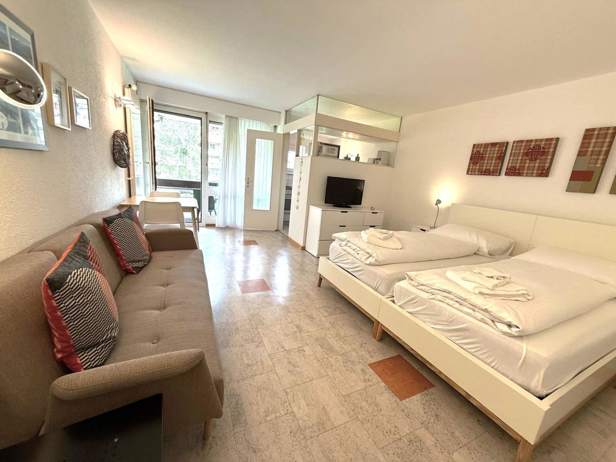 A hotel room with a sofa, a bed, a TV, and a desk.