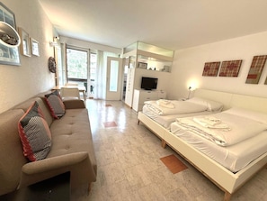 A hotel room with a sofa, a bed, a TV, and a desk. - Fortuna 220 # 2-bed apartment, Dusche, WC 2-Bettwohnung, Dusche, WC by Interhome (Leukerbad)
