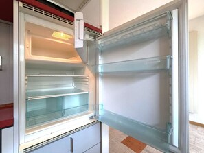 An open refrigerator with multiple shelves and a freezer compartment. - Fortuna 220 # 2-bed apartment, Dusche, WC 2-Bettwohnung, Dusche, WC by Interhome (Leukerbad)