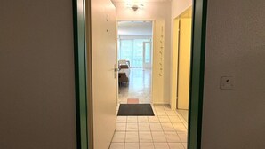 En hall som leder till ett rum med en säng och ett fönster.