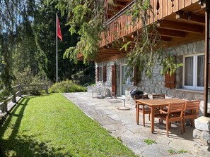 Un edificio in pietra con un balcone in legno, posti a sedere all'aperto e una bandiera.