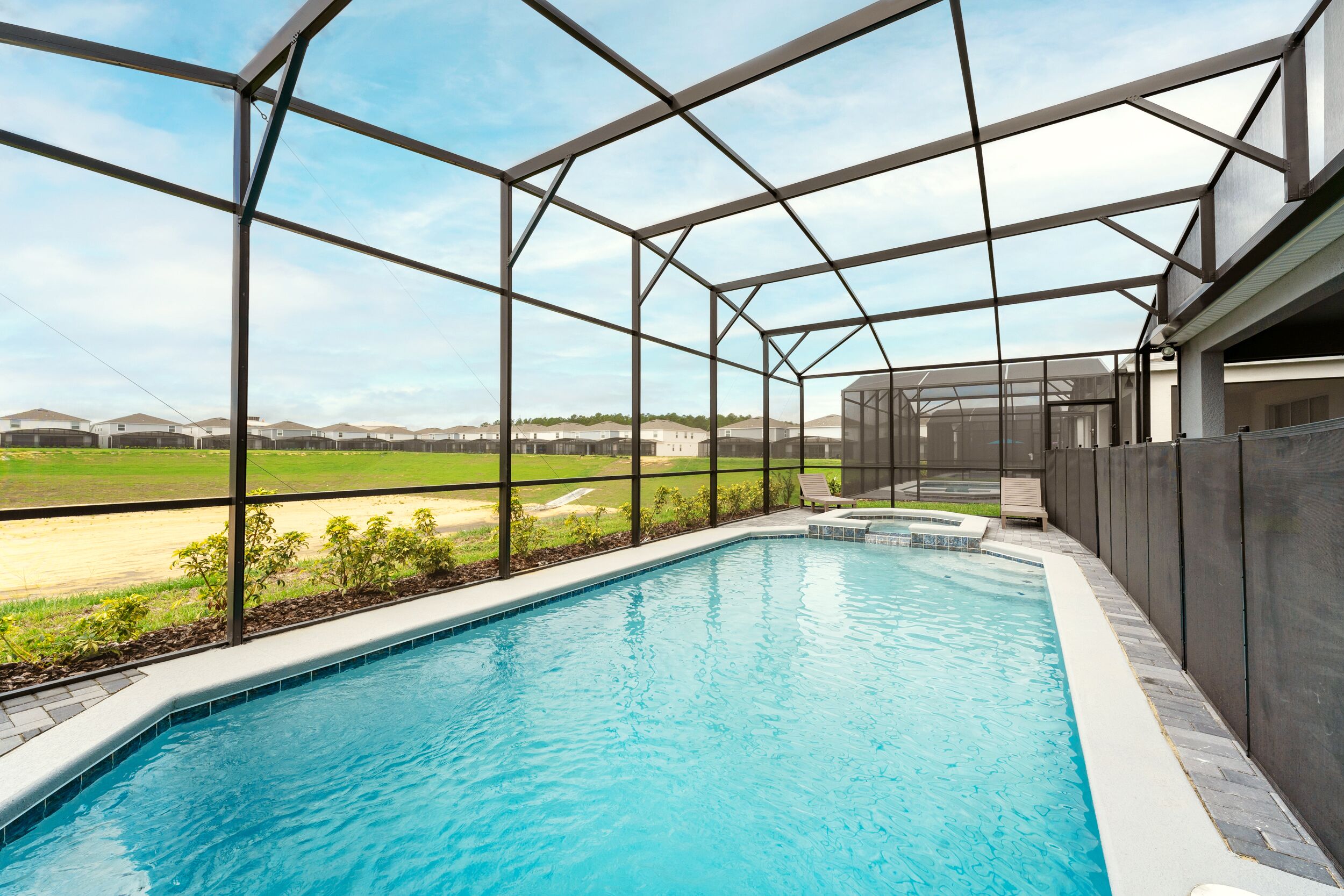 Una piscina con cerramiento de vidrio, vistas a un campo verde y un edificio de diseño moderno.