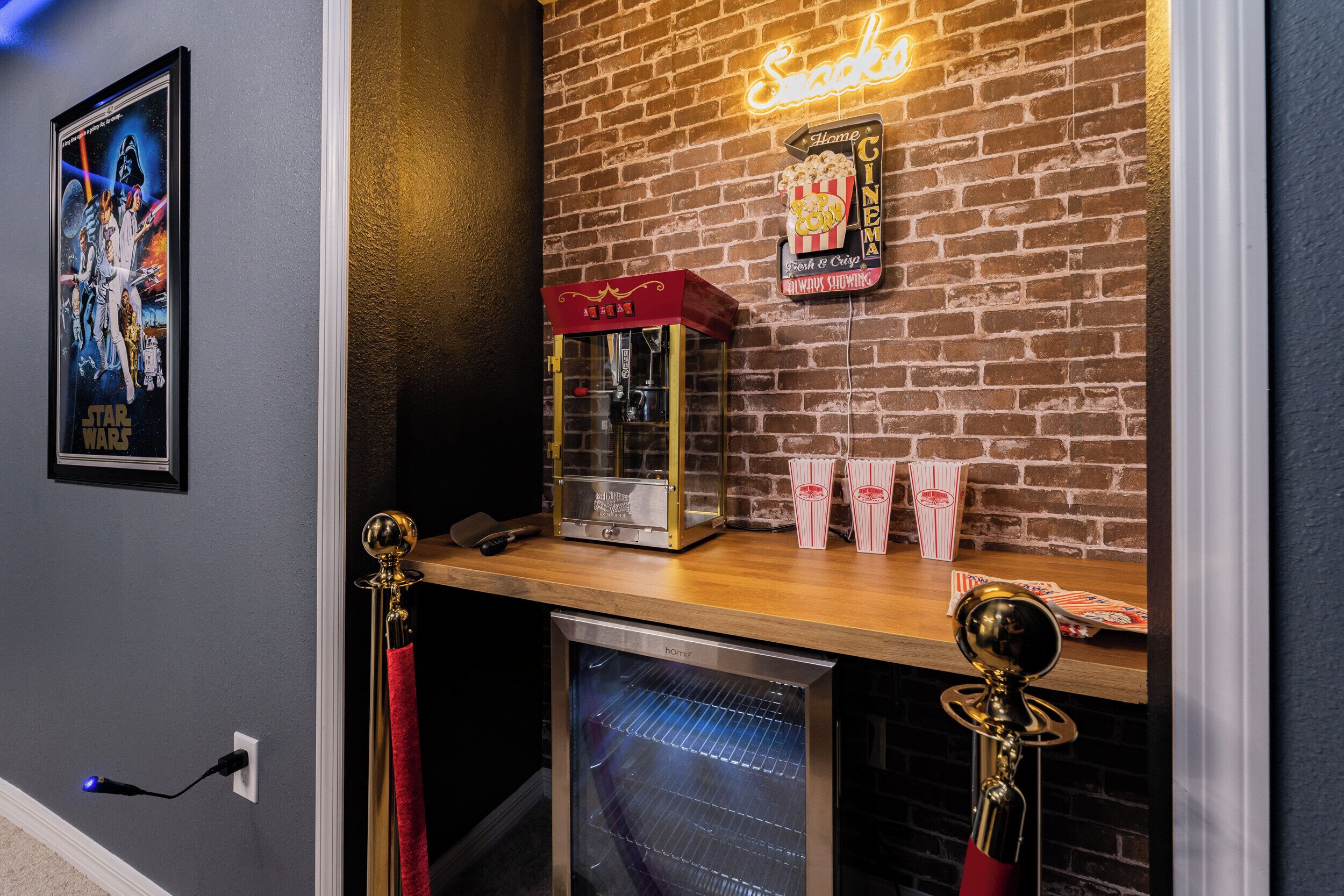 A cinema-themed wall with a neon sign, popcorn machine, and a popcorn box.