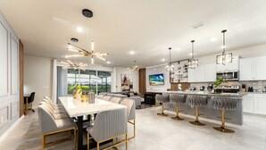 A modern kitchen with white cabinets, a central island with bar stools, and pendant lighting. - 4305-Lana (Davenport)
