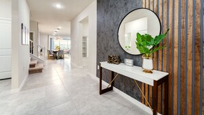 A modern hallway with a staircase, a console table with a mirror, and a potted plant. - 4305-Lana (Davenport)