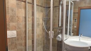 Ein Badezimmer mit einer Duschkabine, einem weißen Waschbecken und einer Toilette.