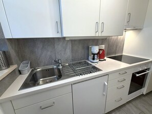 Een moderne keuken met een roestvrijstalen spoelbak, een koffiezetapparaat en een ingebouwde oven.