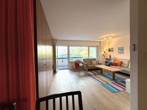 Ein geräumiges Wohnzimmer mit einer Couch, Sesseln, einem Couchtisch und Blick auf einen Balkon.