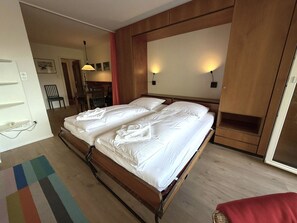 Habitació d'hotel amb un llit doble, un panell de fusta al capçal, una taula petita i una cadira.