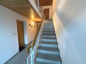 Eine Treppe mit einem hölzernen Geländer und einer Tür am oberen Ende.