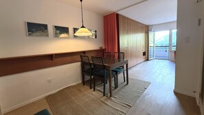A dining area with a table and chairs, a hanging light fixture, and a view through a sliding door to an outdoor balcony. - Salve 8 # 5-bed apartment, Bad, WC 5-Bettwohnung, Bad, WC by Interhome (Leukerbad)