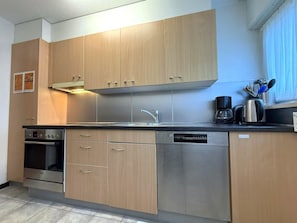 Une cuisine moderne avec des meubles en bois, des appareils en acier inoxydable et une fenêtre agrémentée de rideaux.